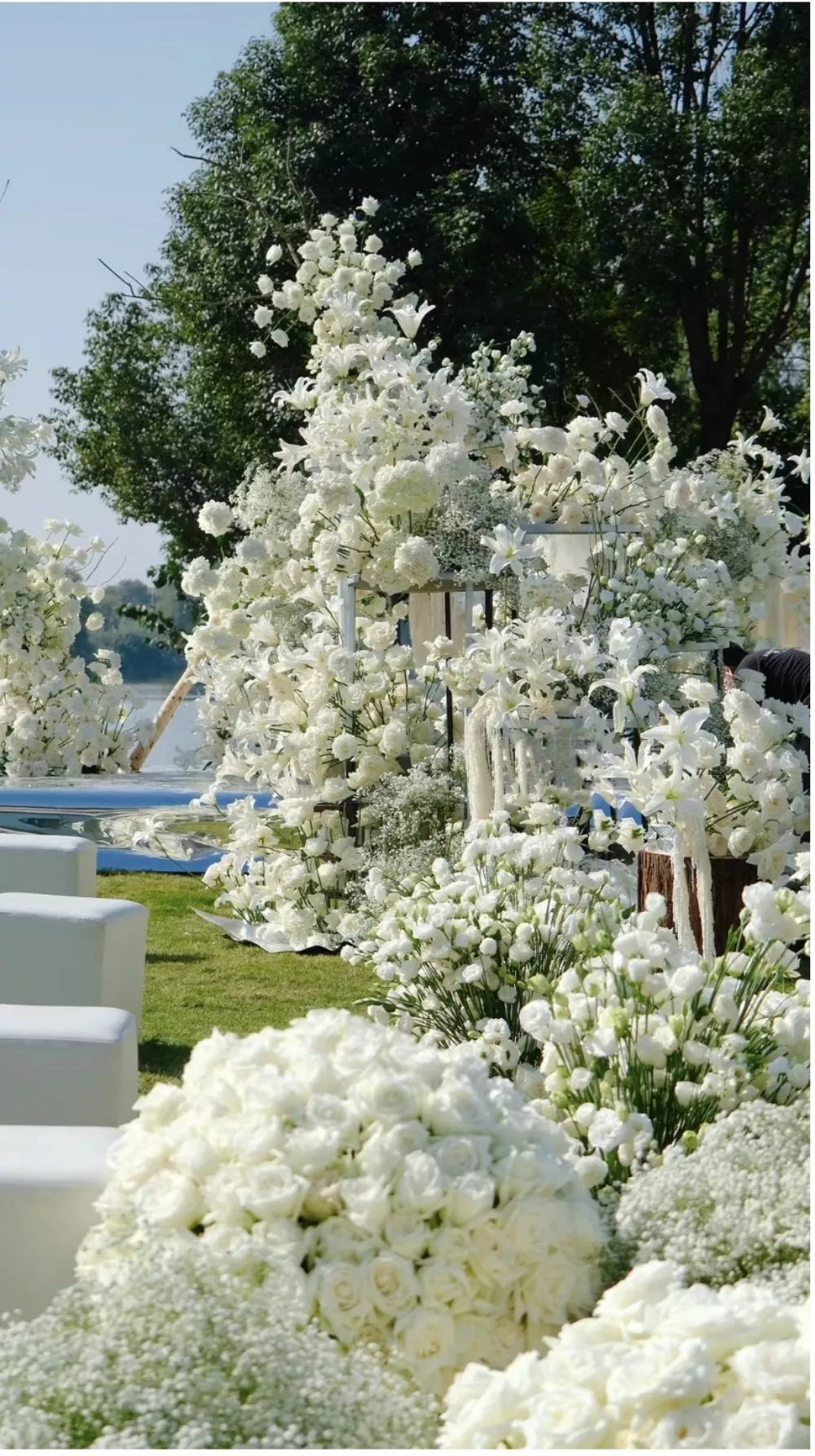 Luxurious wedding aisle lined with white faux flower balls and greenery